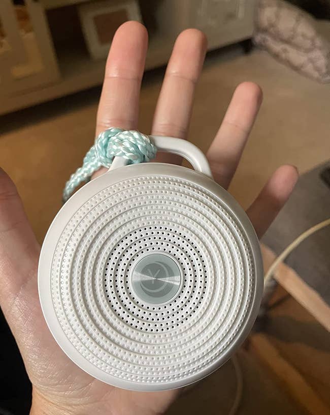 Reviewer holding the small circular noise machine in palm of hand