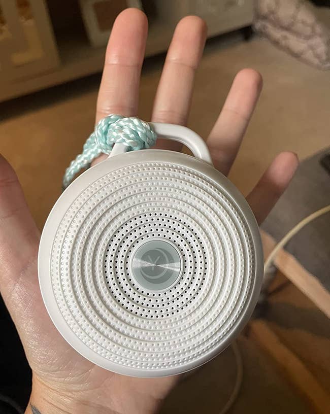Reviewer holding the small circular noise machine in palm of hand
