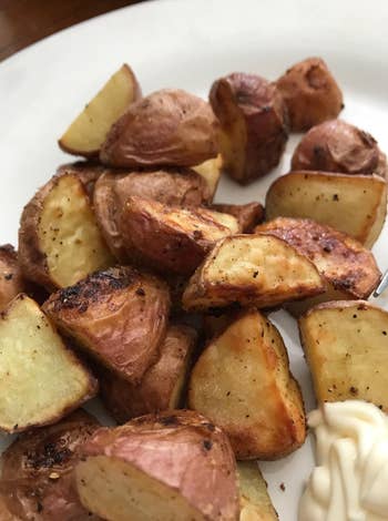 A sheet  of roasted murphy  pieces with a dollop of creamy dipping condiment  connected  the side