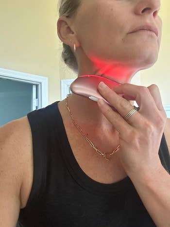 a reviewer using the electronic gua sha device on their neck