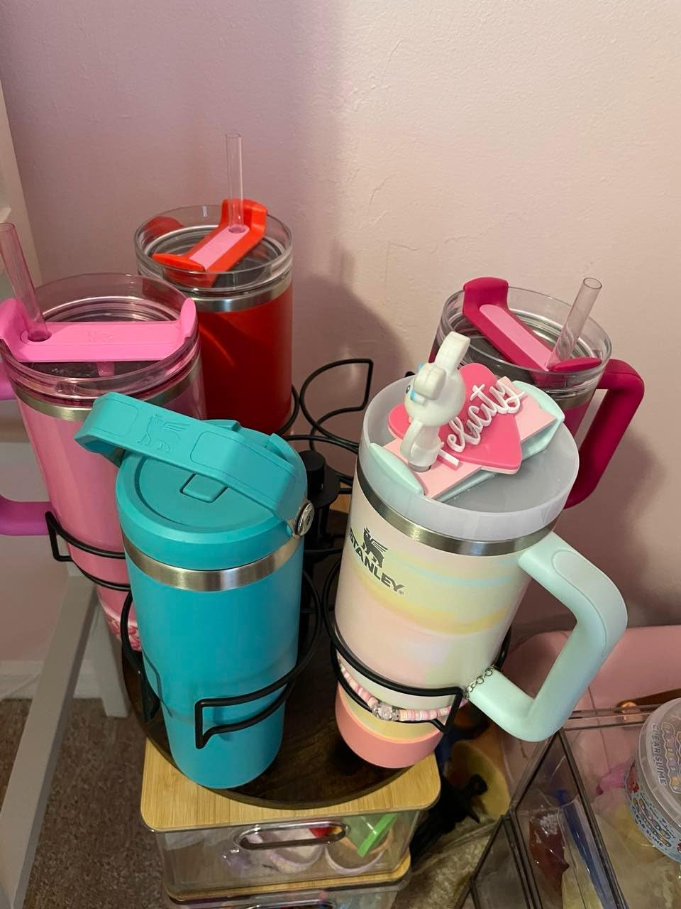 Various Stanley tumblers with handles and straws are displayed on a rack, showcasing different models and colors for shoppers