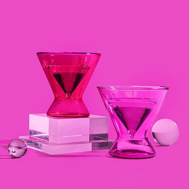 One hot pink and one light pink translucent martini glass against a pink background