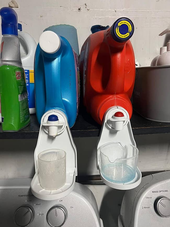 網路行銷 a reviewer photo of two bulk detergent bottles with the cup holders attached to the spouts