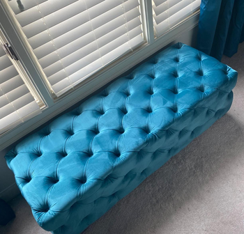 a reviewer photo of the ottoman sitting beneath a window 