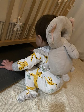 reviewer's baby wearing the elephant backpack cushion