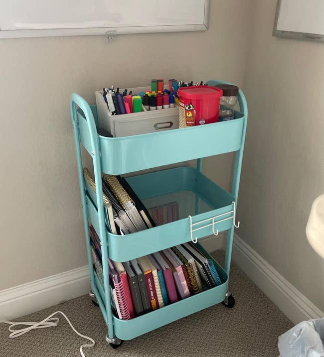 Rolling cart successful country holding pens, markers, notebooks, and bureau supplies, with a powerfulness portion connected the level nearby