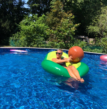 a reviewer sitting in the float and holding the ball in a pool