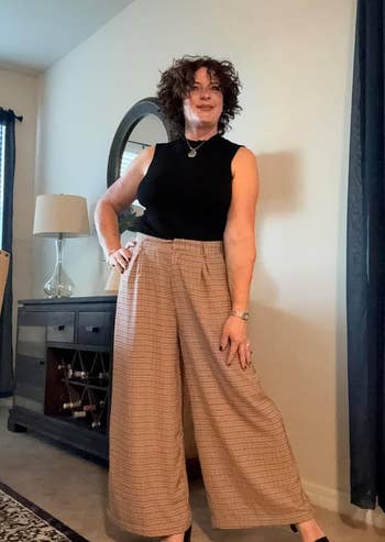 Reviewer in wide-leg trousers and a black top