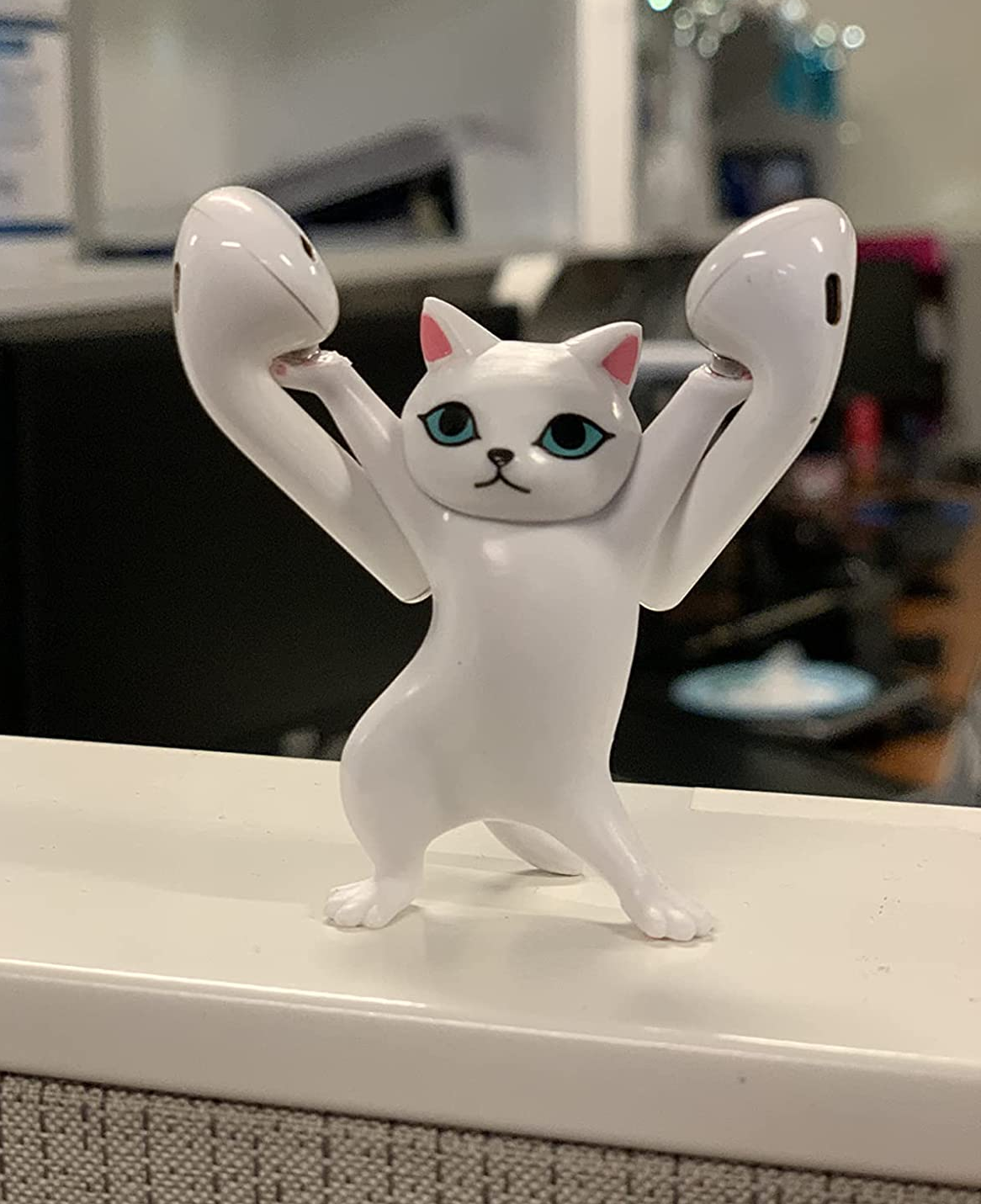 Reviewer's white cat figurine standing on hind legs and holding an airpod on each paw