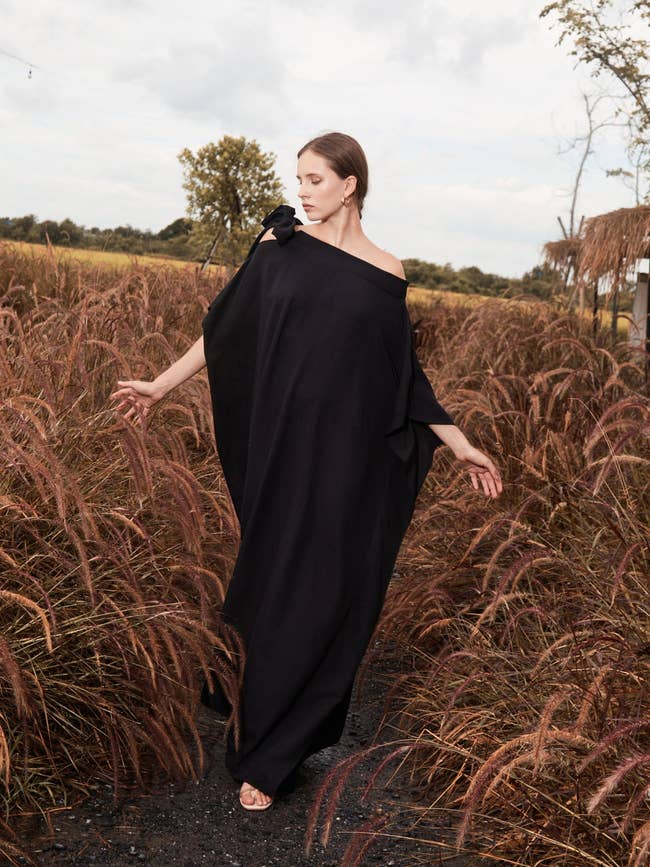a model in a corn field wearing a long black kaftan