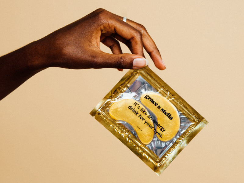 Hand holding a Grace & Stella eye mask packet with text: 