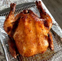 Roasted whole chicken on a wire rack over a baking tray, displaying crispy, golden skin