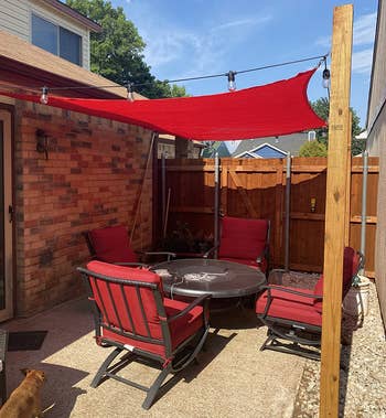 a reviewer photo of a backyard lounge space with a red canopy hung overhead 