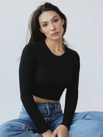model wearing a black long sleeved cropped shirt 