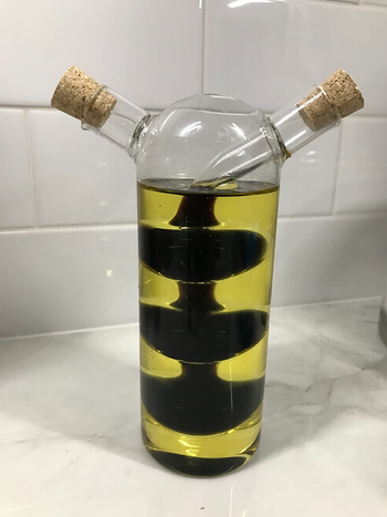 a reviewer photo of an olive oil dispenser with two spouts and an internal chamber for balsamic vinegar 