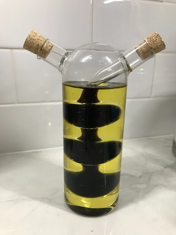 a reviewer photo of an olive oil dispenser with two spouts and an internal chamber for balsamic vinegar