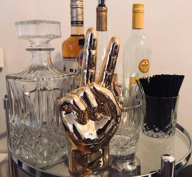 a reviewer photo of a golden peace sign hand statue sitting on a bar cart 