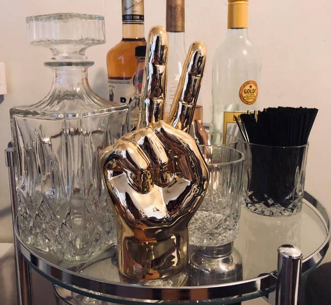a reviewer photo of a golden peace sign hand statue sitting on a bar cart 