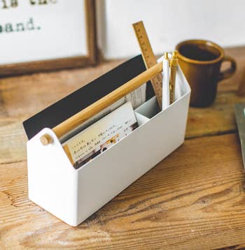 A white small rectangle-shaped organizer with a light wood handle 