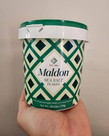 Reviewer holding a container of Maldon Sea Salt Flakes 