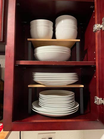 Reviewer's kitchen cabinet with neatly stacked white bowls and plates on wooden shelves. Perfect for organizing dinnerware