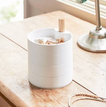 Stackable rotating jewelry organizer with wooden handle on a wooden table