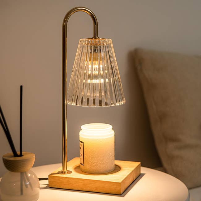 Elegant table lamp with ribbed glass shade on a modern wooden base next to a white candle