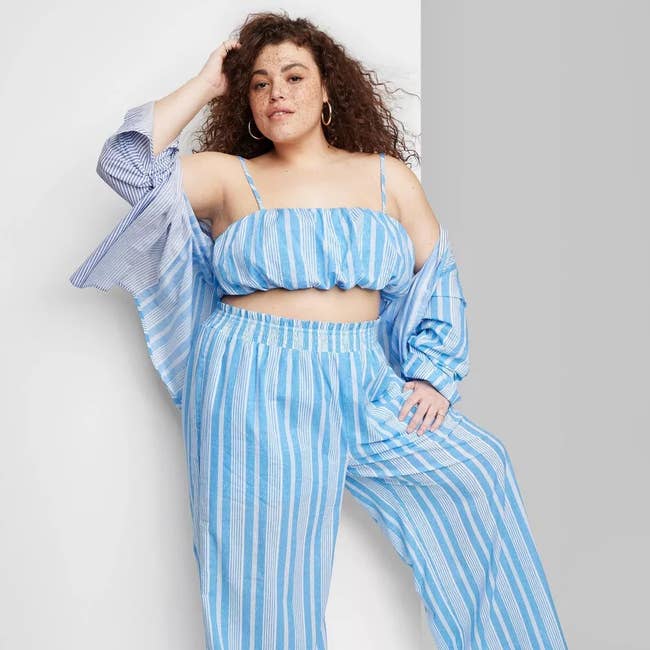 a plus size model wearing the blue multi-striped bubble hem top with matching pants and button down top