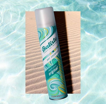 a bottle of dry shampoo against a sandy and watery background