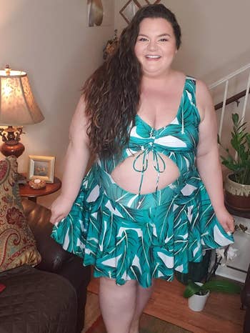 reviewer wearing the palm leaf-print swimdress with a V-neck and cutout at the stomach