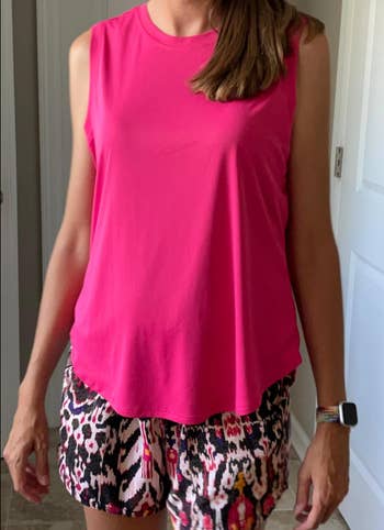 Person wearing a sleeveless apical  and patterned shorts, lasting  indoors, showcasing casual summertime  attire suitable for upbeat buying  outings