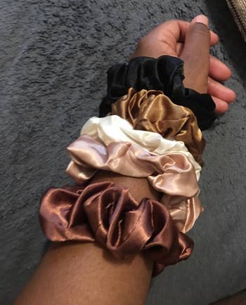 reviewer wearing brown, blush, white, caramel, and black scrunchies on their writst