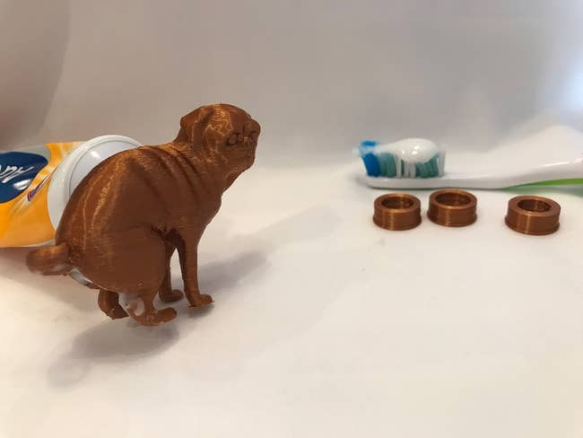 copper color 3d printed pug shaped topper that has toothpaste come out of the butt