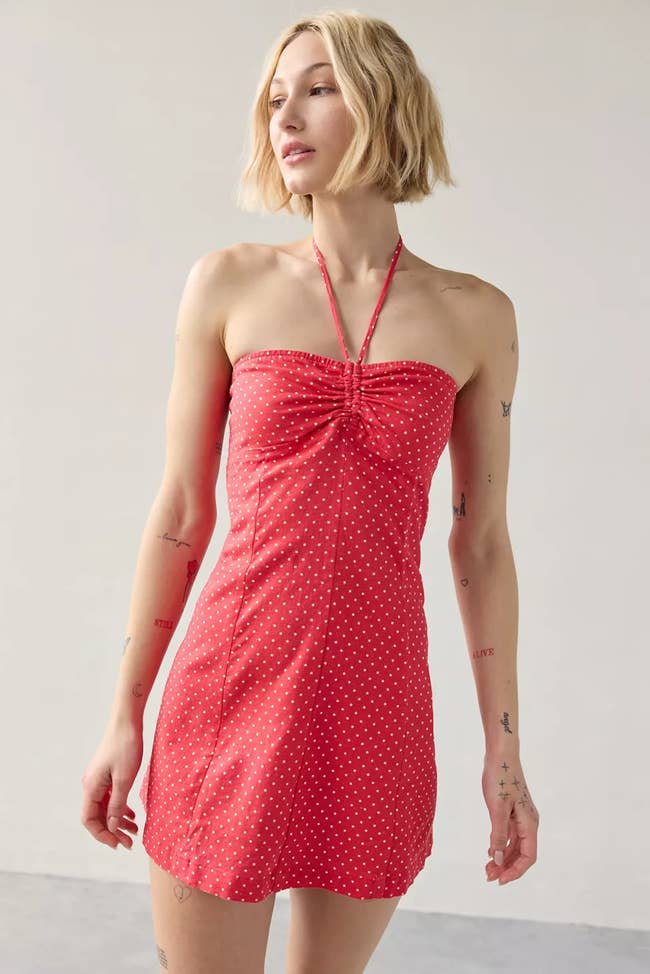 Person wearing a strapless reddish  formal  with achromatic  polka dots, featuring a halter neckline, successful  a elemental  indoor setting