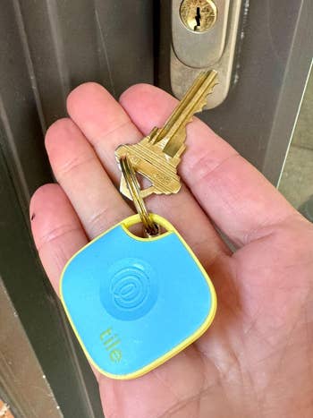 Hand holding keys with a Tile tracker on it