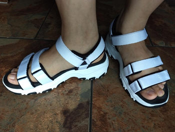 Reviewer wearing white velcro sandals with foam platform on tile floor