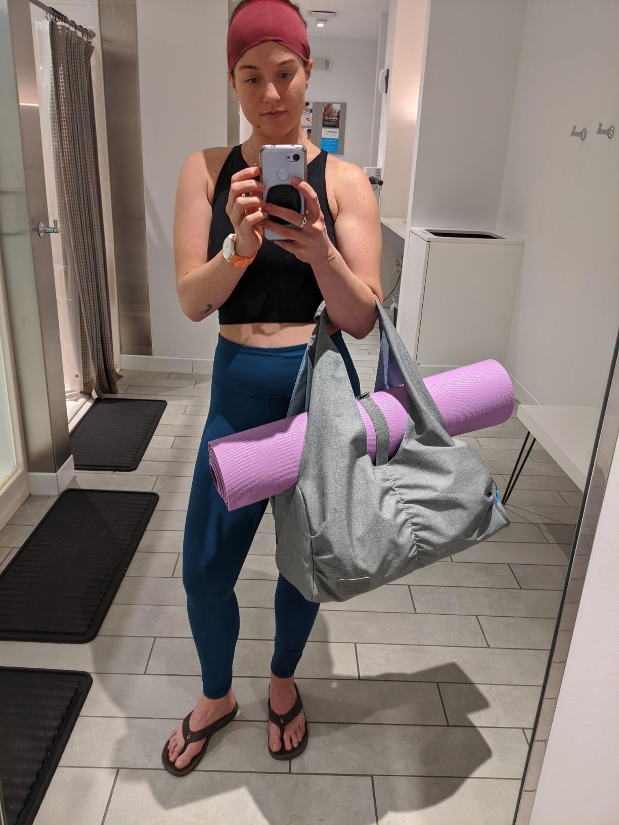 reviewer carrying a gray gym bag with slot holding folded purple yoga mat