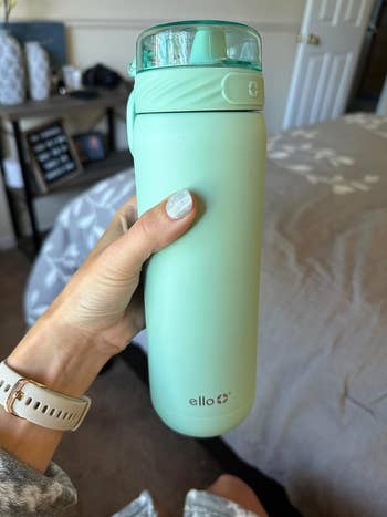 a reviewer showing their mint green water bottle