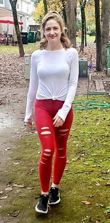 reviewer in casual outfit consisting of a white long-sleeve top and red leggings with horizontal cuts