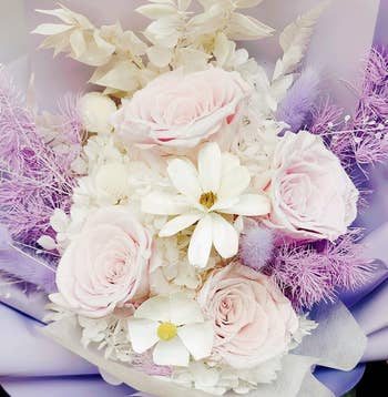 another reviewer's close up of bouquet with white and light pink roses, white daisies, and delicate feathery accents. Suitable for gifting