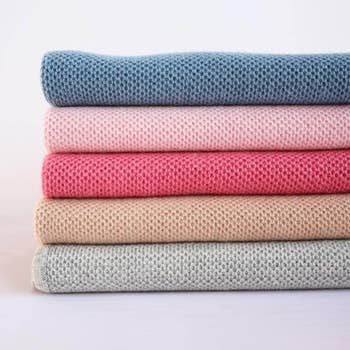 a stack of colored knit blankets