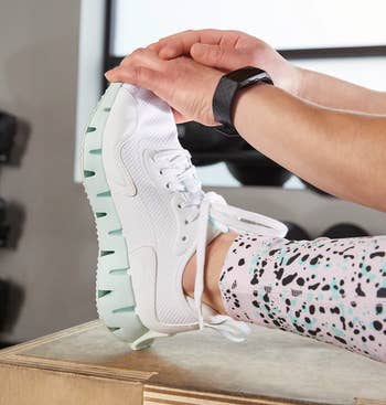 model wearing sneakers while stretching at gym