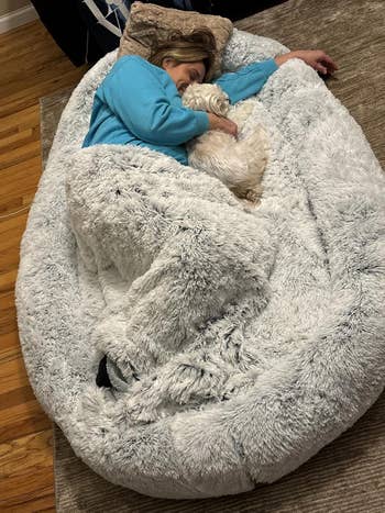 Person successful  cozy outfit sleeps successful  large, plush legume  container  chair, cuddling a tiny  dog, illustrating comfortableness  and benignant   perfect  for location  relaxation