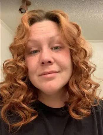 Reviewer with red voluminous curls after using product and a black top 
