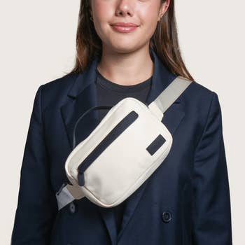 Woman wearing a dark blazer and a white crossbody bag with a sleek design