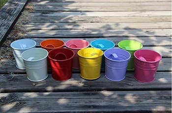 A row of colorful buckets in different shades on a wooden surface