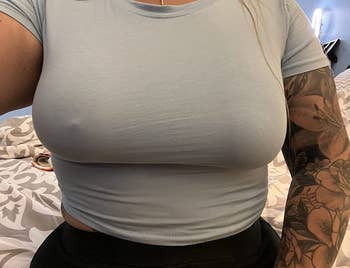 a reviewer wearing a T-shirt with a nipple cover applied on one breast and not the other 