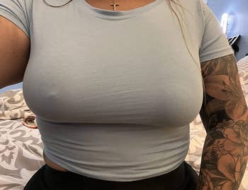 a reviewer wearing a T-shirt with a nipple cover applied on one breast and not the other 