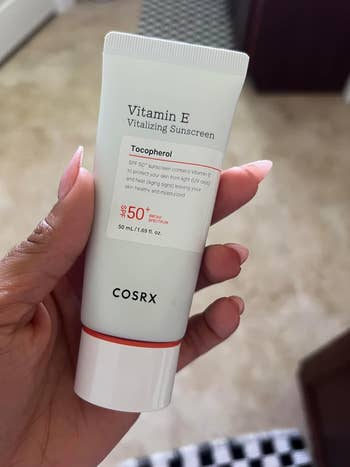 Hand holding the sunscreen tube