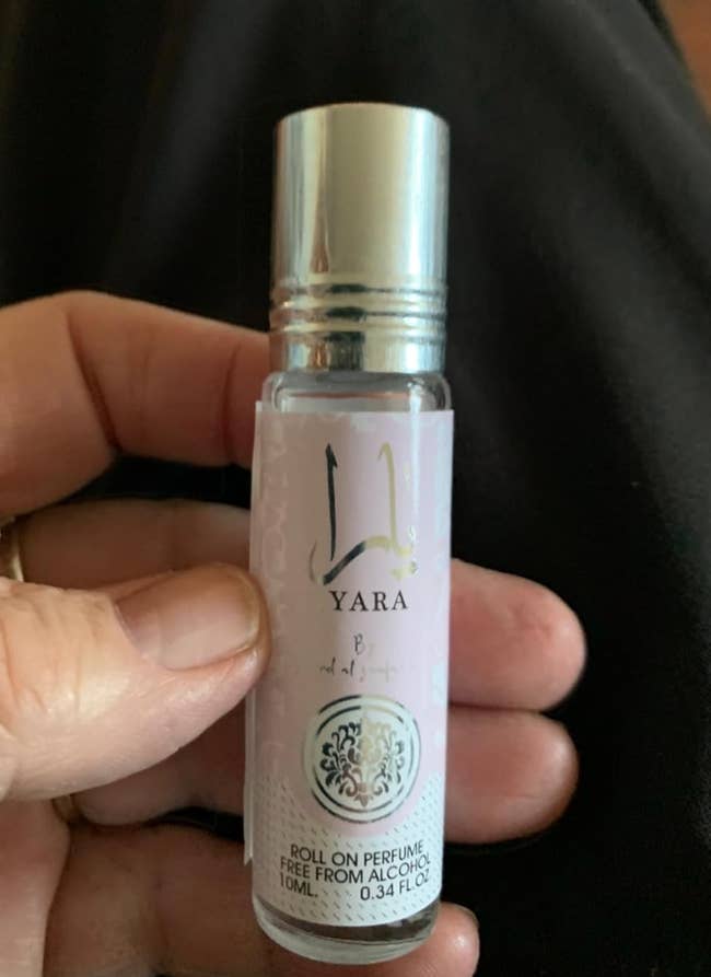 Person holding a tiny  roll-on perfume vessel  labeled 